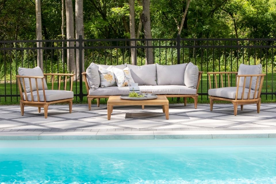 Outdoor patio next to pool with comfortable outdoor couch and chairs